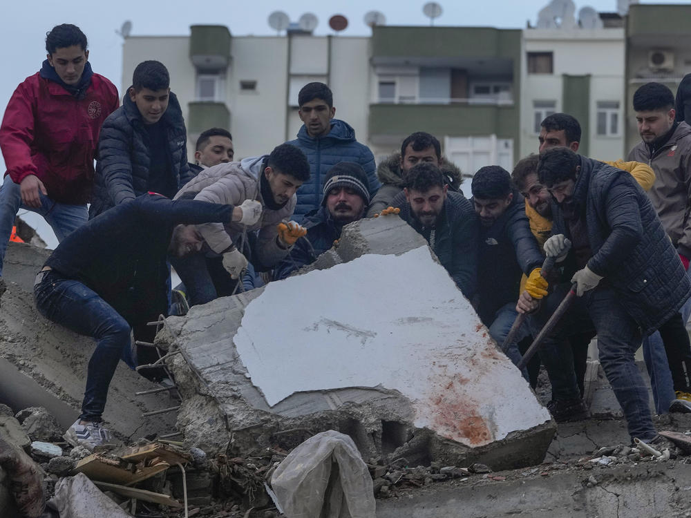 Men search for people among the debris in a destroyed building in Adana, Turkey, Monday.