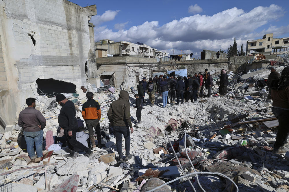 People on Tuesday search through the rubble of collapsed buildings where a newborn girl was found in the town of Jinderis.