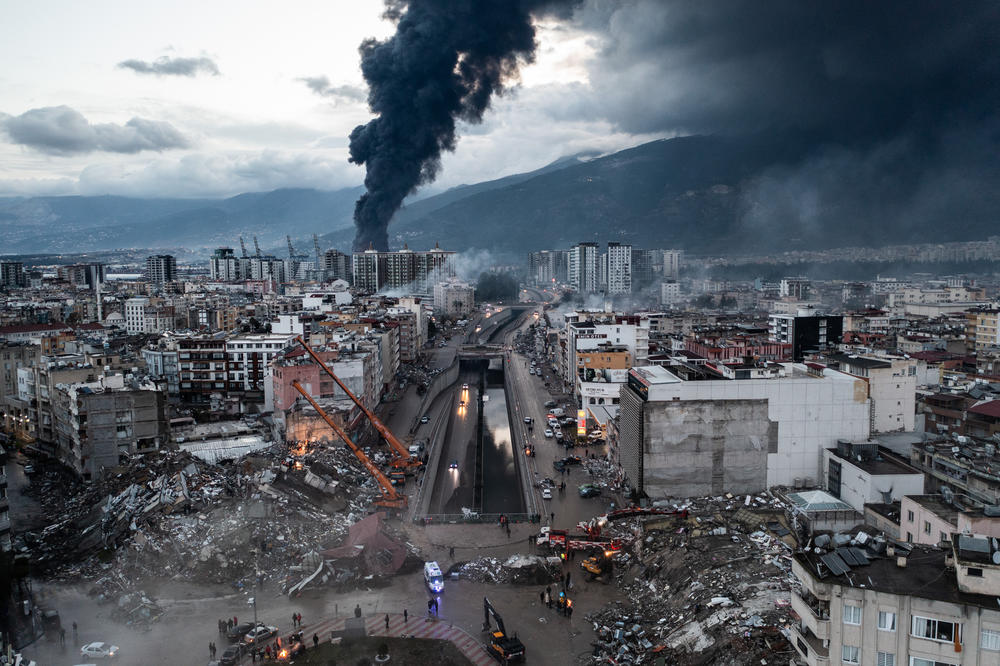 Smoke billows from the Iskenderun Port as rescue workers search the site of a collapsed building in Iskenderun, Turkey on Tuesday. The quakes caused widespread destruction in southern Turkey and northern Syria and were felt in nearby countries.
