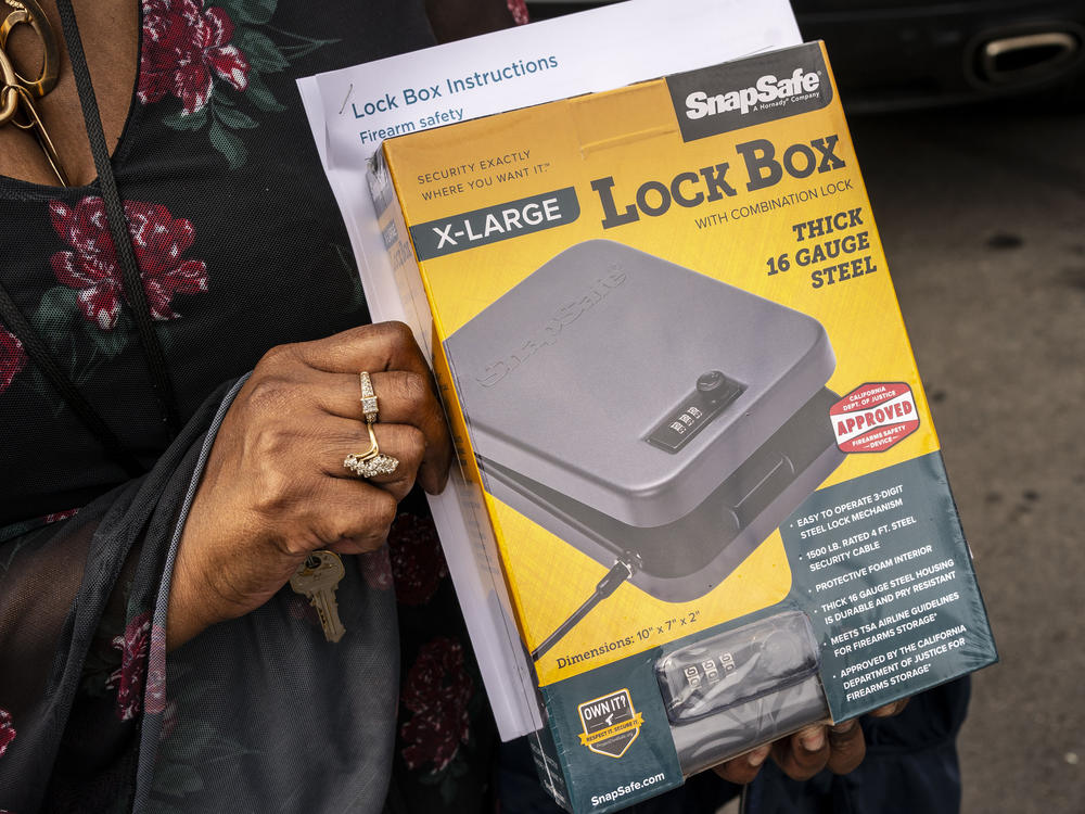 An attendee holds their free lockbox during a gun lockbox giveaway event on June 4, 2021 in Seattle, Wash.