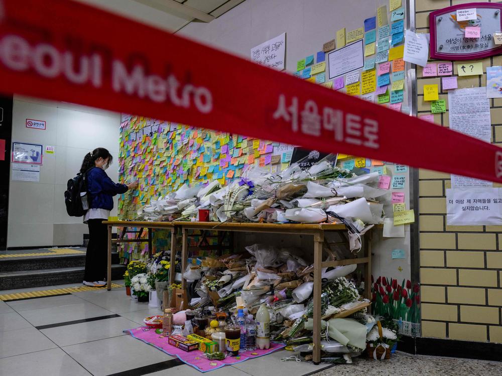 A woman pays her respects as she displays a note near the entrance to a female lavatory at Sindang station in Seoul on Sept. 19, 2022. Seoul Metro employee Jeon Joo-hwan was sentenced Tuesday for stabbing his colleague to death in the metro station's women's public toilet the day before a court was set to sentence him on charges of stalking her.