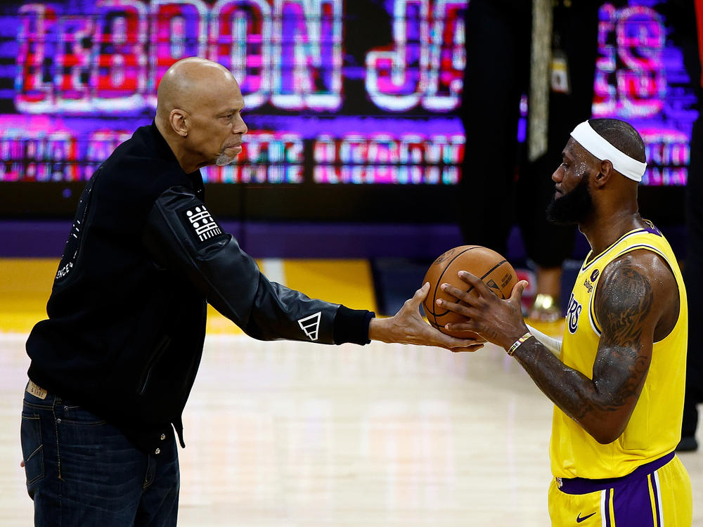 Kareem Abdul-Jabbar (left) hands LeBron James a basketball celebrating James' all-time NBA scoring record Tuesday night in Los Angeles.