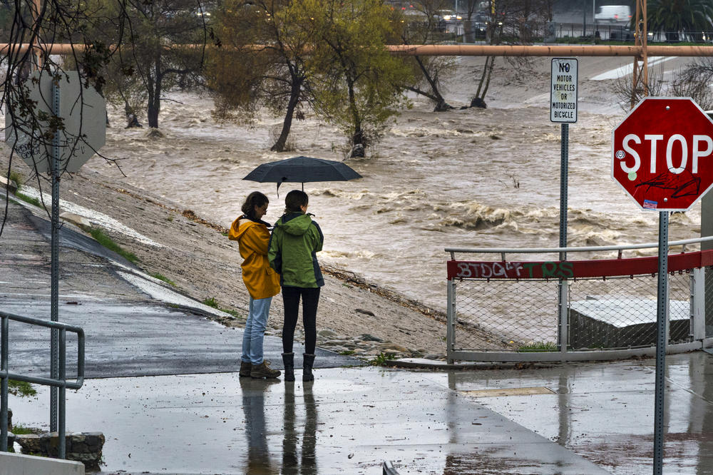 People watch rain water flowing downstream at the Los Angeles River in Los Angeles this January.