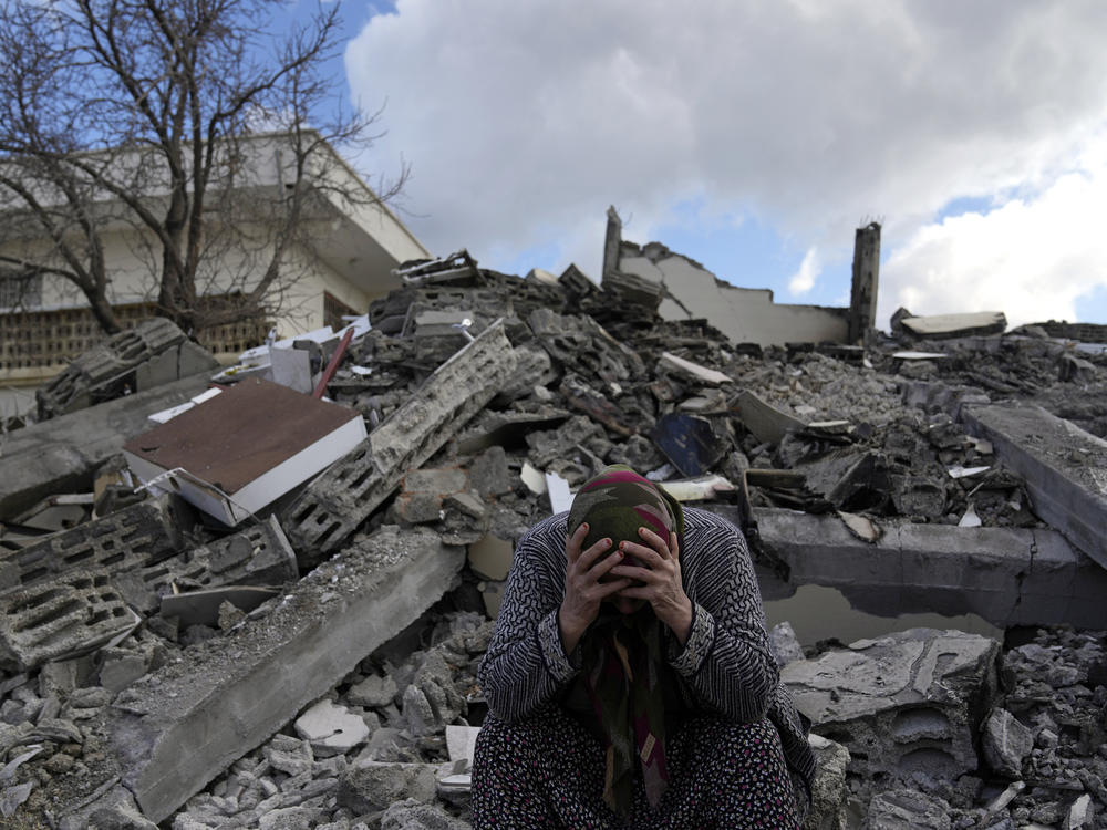 A woman sits on the rubble as emergency rescue teams search for people under the remains of destroyed buildings in the town of Nurdagi on the outskirts of Osmaniye in southern Turkey on Tuesday.