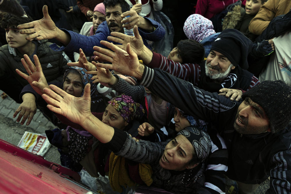 People reach out for aid from volunteers in Antakya, southern Turkey, on Wednesday, after Monday's earthquake left many residents homeless and without access to basics in the middle of winter.