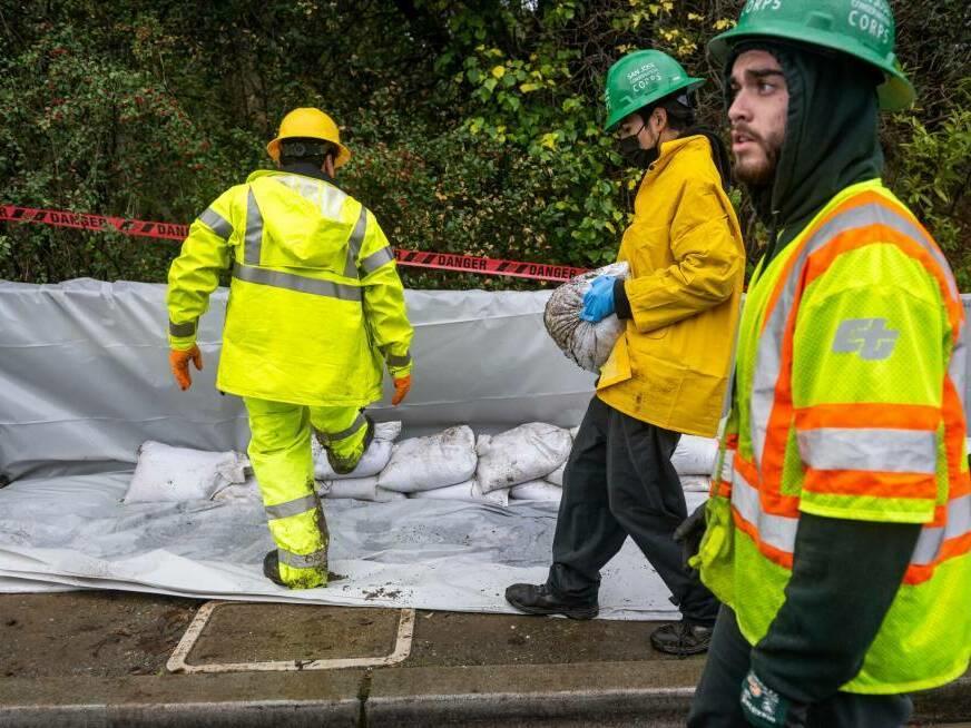 Members of the San José Conservation Corps pile sandbags along the San Francisquito Creek in East Palo Alto on Jan. 4, 2023. The creek spilled over its bank and into a nearby community during the storm on New Years Eve.