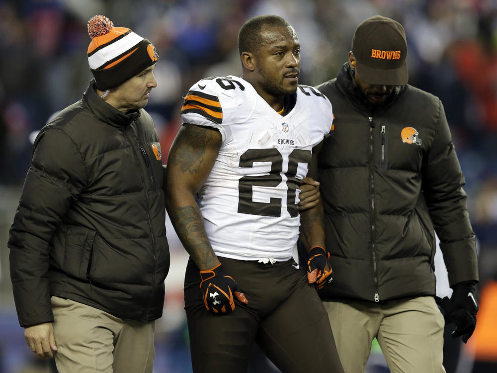 Cleveland Browns running back Willis McGahee is helped from the field after getting injured during an NFL game against the New England Patriots on Dec. 8, 2013. Ten retired NFL players, including McGahee, accused the league of lies, bad faith and flagrant violations of federal law in denying disability benefits in a potential class action lawsuit filed on Thursday in Baltimore.