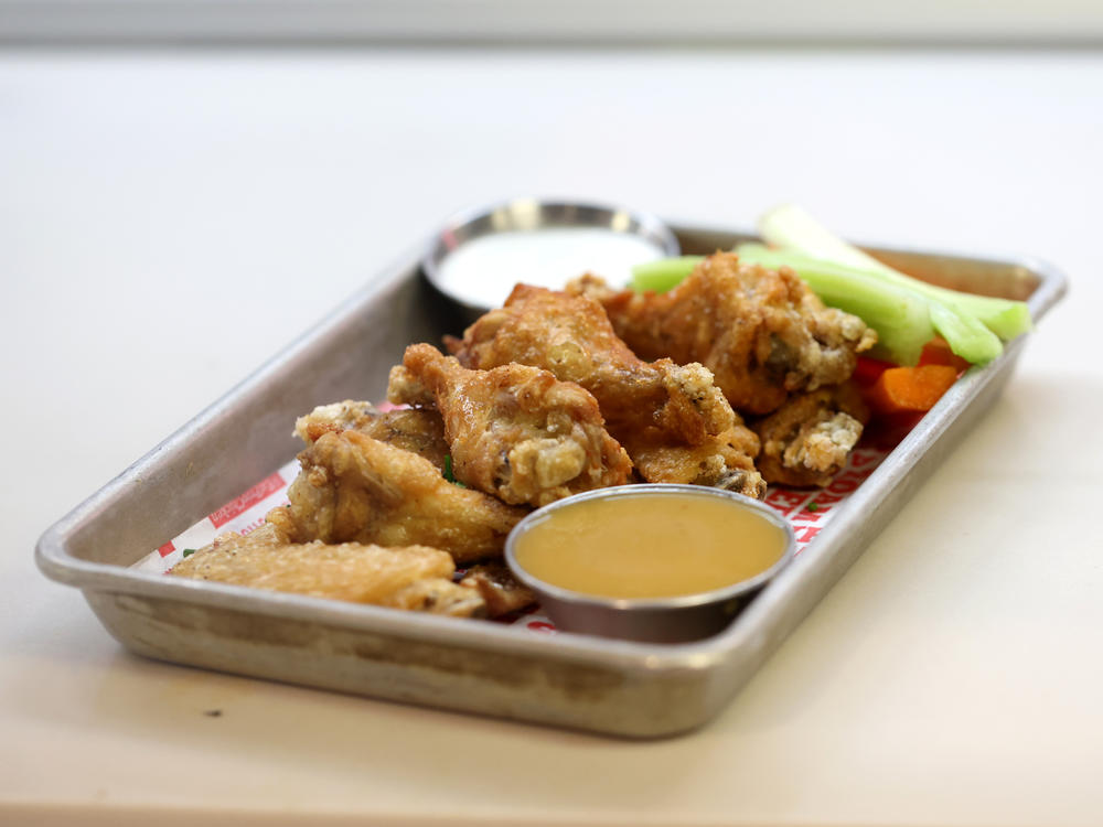 An order of Buffalo chicken wings sits on a counter at a restaurant in San Francisco on Feb. 11, 2022. Party trays of frozen chicken wings are cheaper than last year, according to the USDA. The National Chicken Council expects Americans to gobble up 1.45 billion wings this weekend.