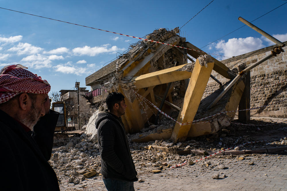 Locals walk past a damaged water tank in the Syrian town of Sawran, on Friday, days after a massive earthquake hit the region.
