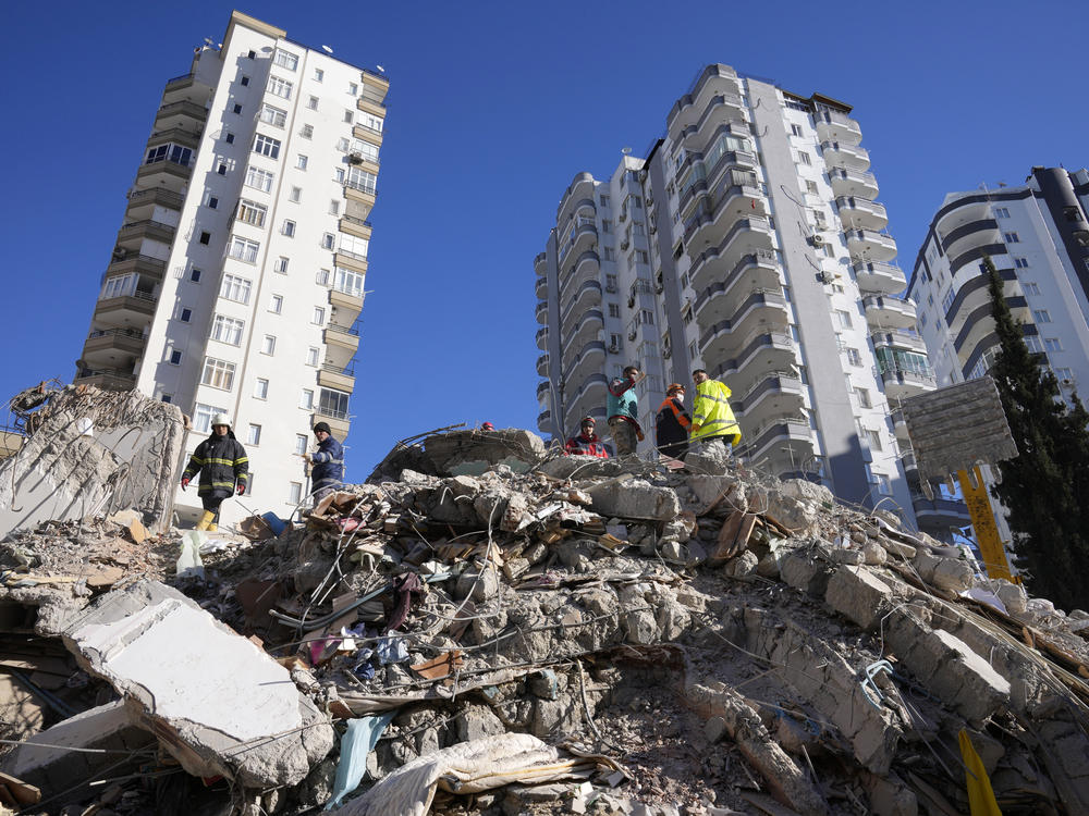Emergency teams search for people in the rubble of a destroyed building in Adana, southern Turkey, Tuesday, Feb. 7, 2023. For Syrians and Ukrainians fleeing the violence back home, the earthquake that struck in Turkey and Syria is but the latest tragedy.