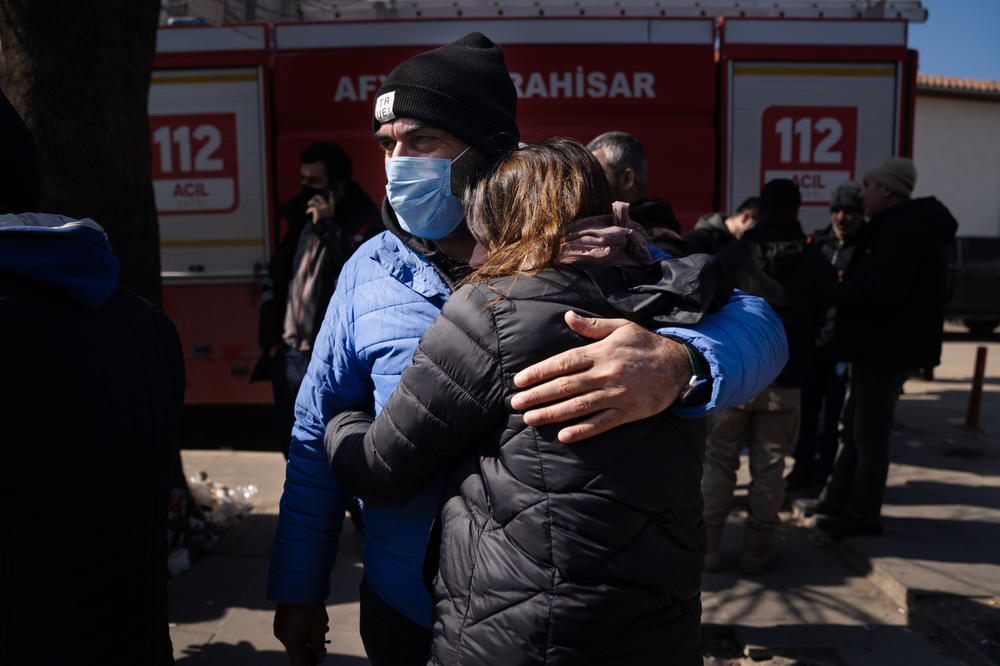 Sehmuz Sonmez holds his niece, Yasemin Arslan, as they wait with other family members outside a collapsed apartment building in Islahiye. Their relative remains unaccounted for in what's left of the building.