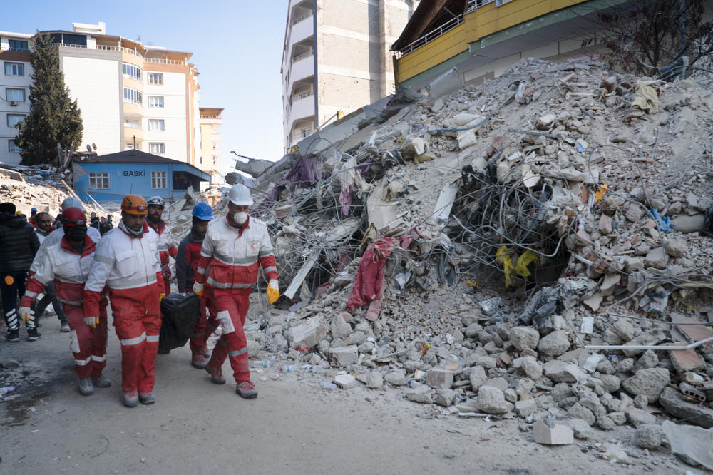 Workers transport a body out of the rubble of a building that collapsed in Islahiye.