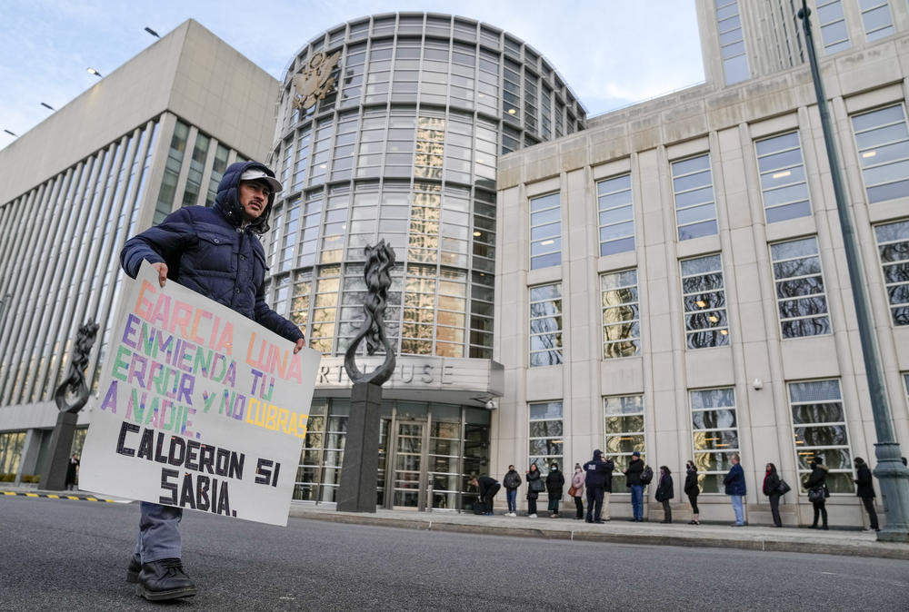 A protestor stands outside Federal court in Brooklyn on January 17 with a sign that says, 