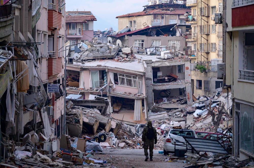 A Turkish soldier walks by destroyed buildings in Hatay, on Sunday, nearly a week after a 7.8 magnitude earthquake struck the country's southeast.