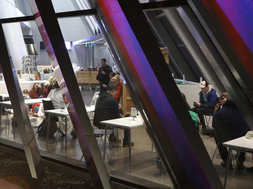 People are seen inside the Broad Art Museum near Berkey Hall on the campus of Michigan State University as they shelter in place, late Monday, in East Lansing, Mich.