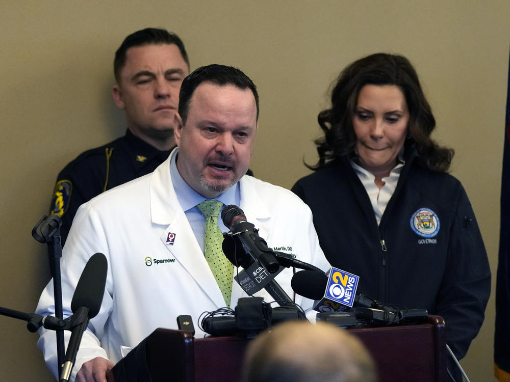 Dr. Denny Martin, the acting chief medical officer at Sparrow Hospital in East Lansing, Mich., got emotional while addressing the media on Tuesday following a shooting at Michigan State University. Behind him is Gov. Gretchen Whitmer.