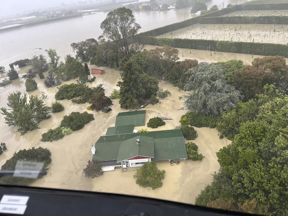 In this image released by the New Zealand Defense Force on Wednesday, Feb. 15, people stand on a rooftop of a home waiting to be winched to safety by helicopter in the Esk Valley, near Napier, New Zealand. The government declared a national state of emergency Tuesday after Cyclone Gabrielle battered the country's north in what officials described as the nation's most severe weather event in years.