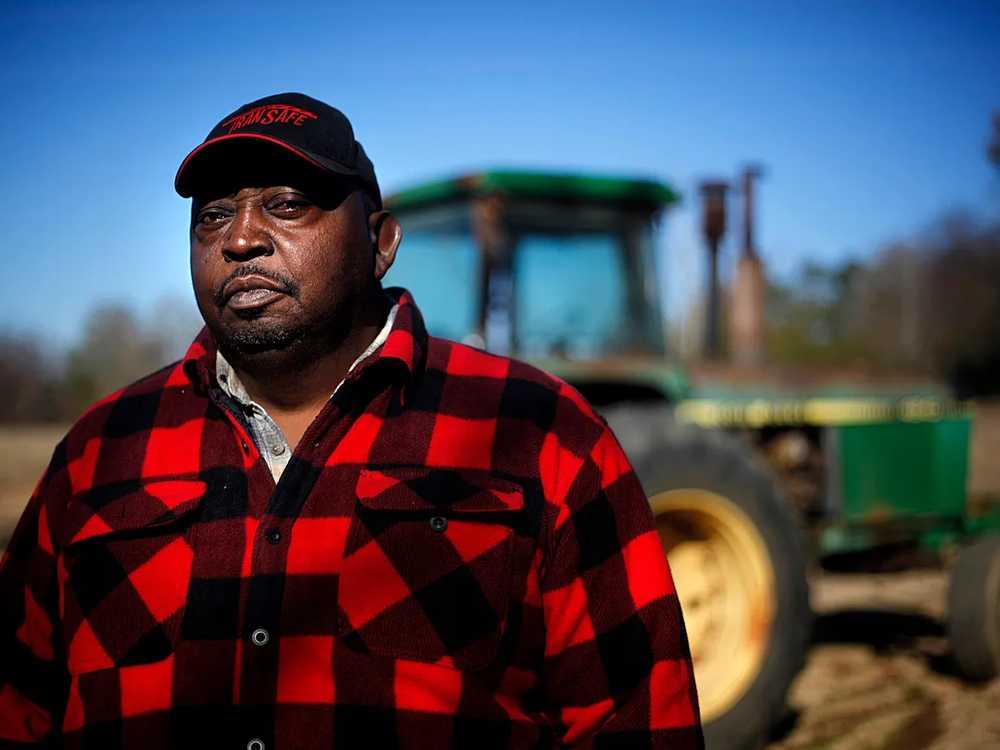 Lucious Abrams, a plaintiff in the Pigford v. Glickman class action lawsuit, stands in front of a tractor on his Georgia farm.