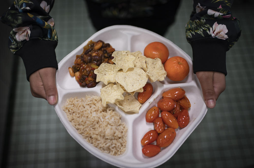 A seventh grader carries her plate of three-bean chili, rice, mandarins and cherry tomatoes and baked chips during her lunch break at a local public school, on Feb. 10 in the Brooklyn borough of New York.