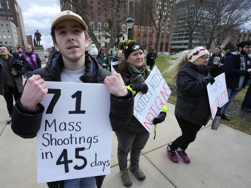 Austin Hunt holds a sign with current and former Michigan State University students during a rally at the state Capitol in Lansing, Mich., Wed., Feb. 15, 2023, after a gunman opened fire on the Michigan State University campus Monday night.