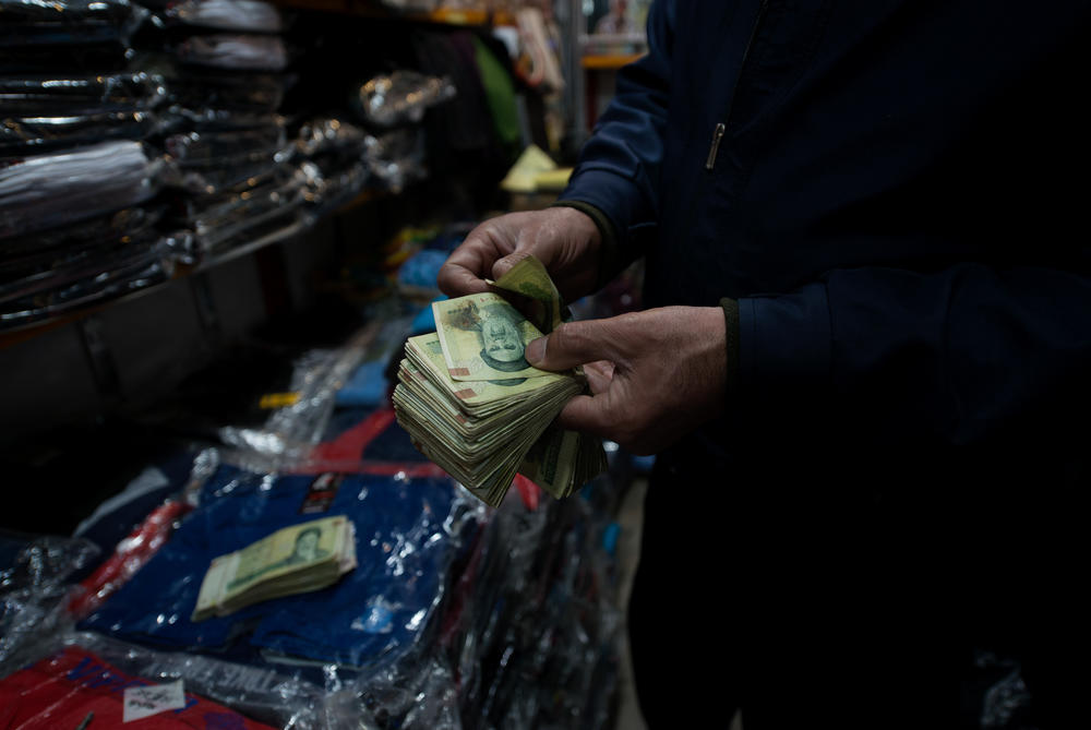 A bazaar shopkeeper counts Iranian bank notes.