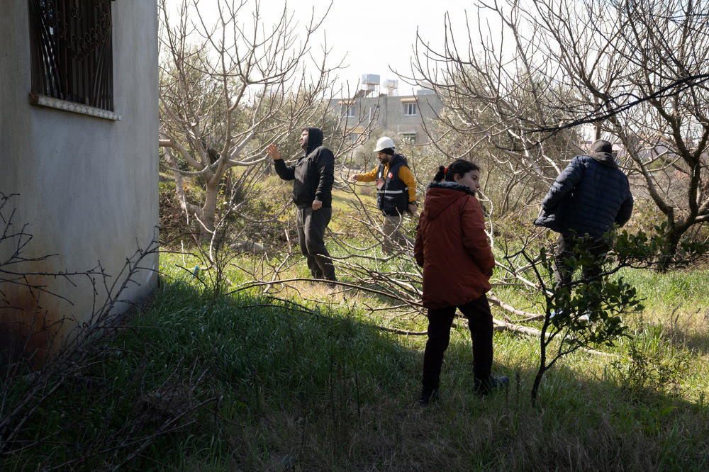 Onur Tezcan Okut walks with Samir Kanar (left) around the building where his family lives to inspect for damage.
