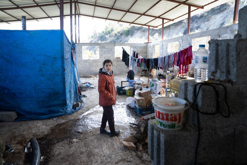 Zeynep Kanar, 9, stands in the barn where her family is staying while they are to afraid to move back into their home. They have rigged up tarps to make a tent.