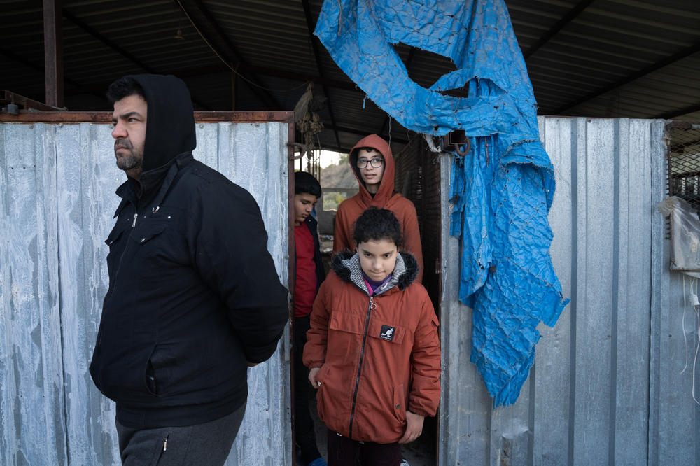 Samir Kanar (left) and three of his children walk out of the barn where they are staying.