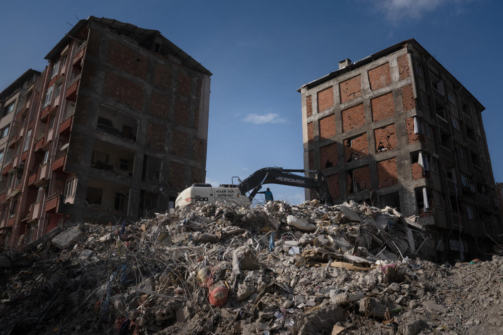 A crane digs through rublle as people are still looking for bodies of the dead in Antakya, Turkey.