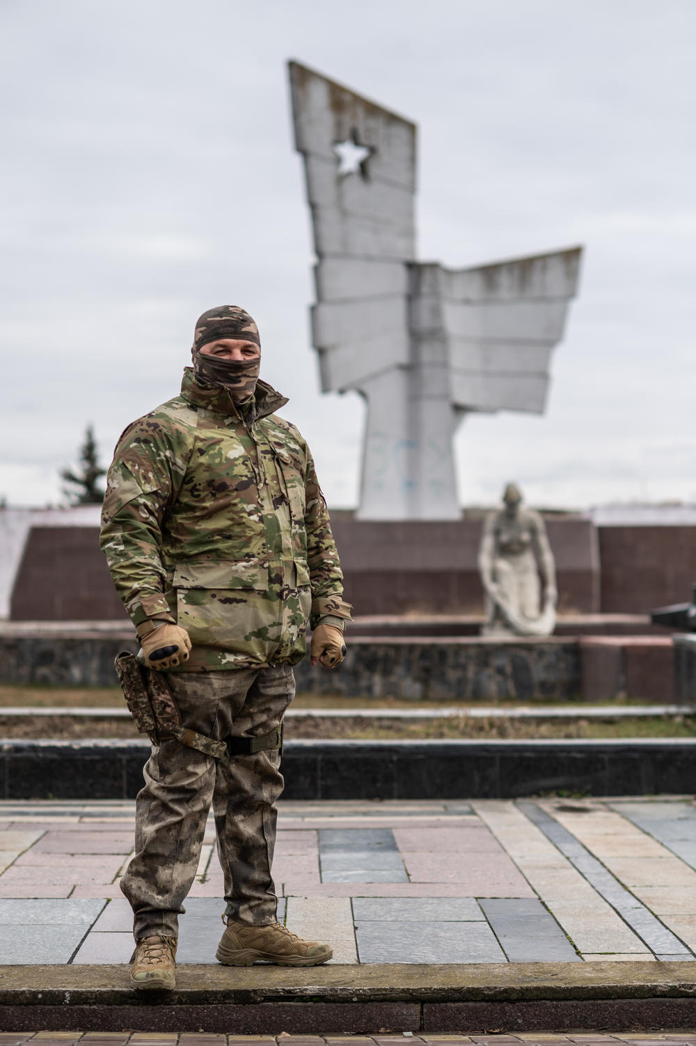 Serhiy, a soldier who cannot show his face or reveal his last name as he has family in occupied territory, poses in front of a World War II memorial in Kherson, Ukraine.