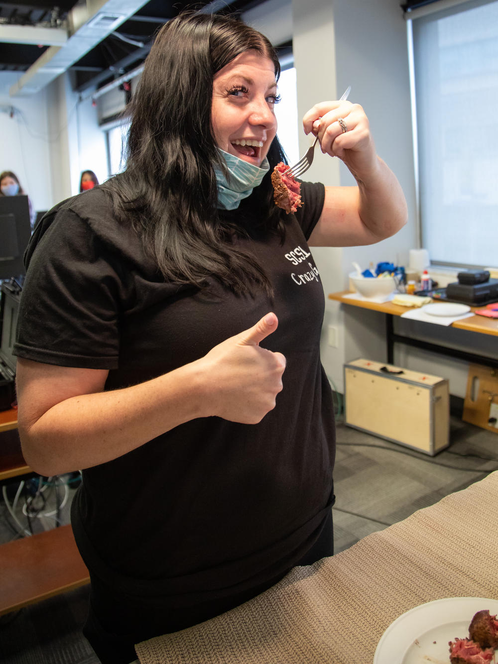 Rendulic gives a thumbs up while holding a fork with a piece of steak with her affected arm.