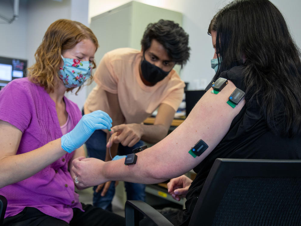 University of Pittsburgh kinematic occupational therapist Amy Boos (left) and Carnegie Mellon University graduate student Nikhil Verma (middle) connect muscle activation sensors on Rendulic.