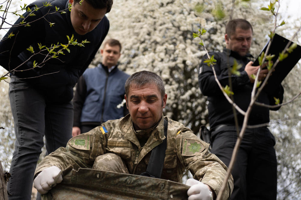 A forensic team looks under the clothing of the Russian soldier to assess the cause of death in April.