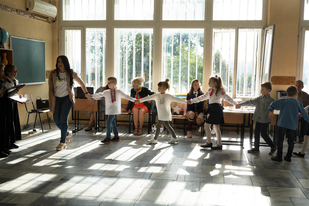 At a small private school in Dnipro, one of just a handful of schools offering in-person classes in the city, a teacher leads new first-graders to the front of the room in a welcoming ceremony in September.<em></em>