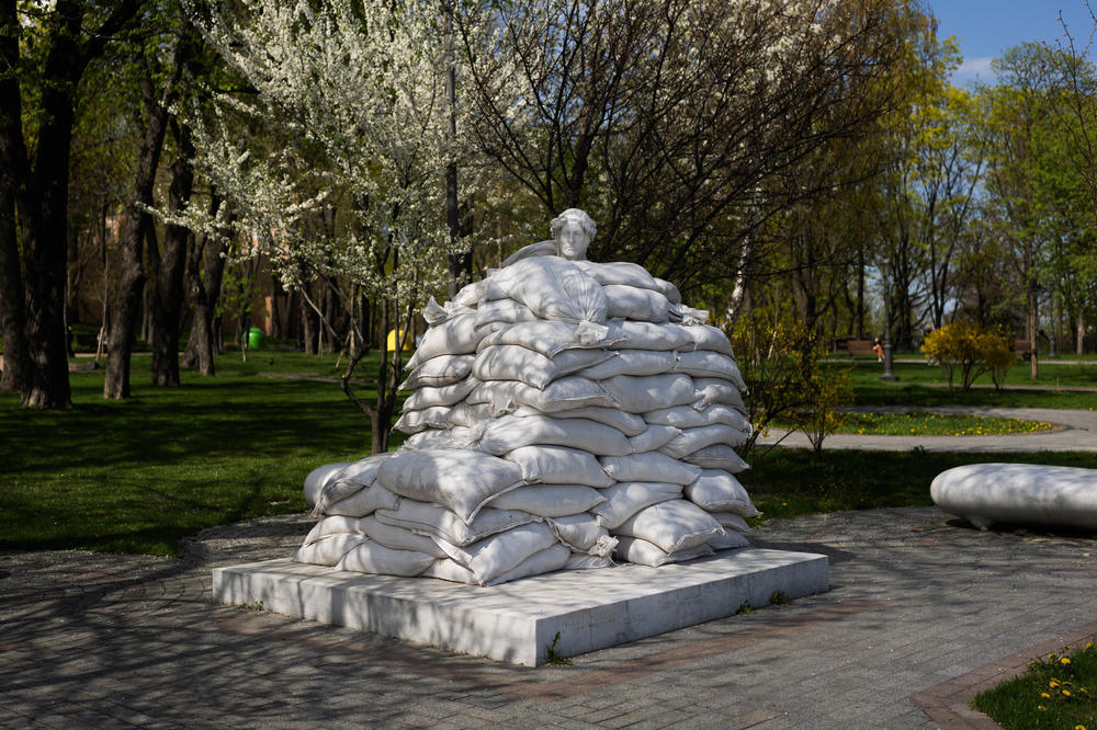 Sandbags surround a statue on a spring day in Kyiv.