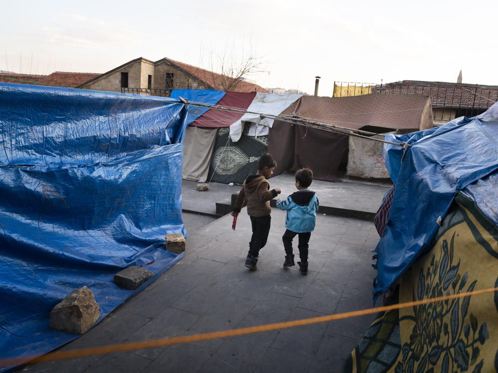 Two boys walk through a small tent encampment in Gaziantep, Turkey, on Thursday, Feb. 16. People have set up makeshift tents since they are too afraid to return to their homes after the earthquake.