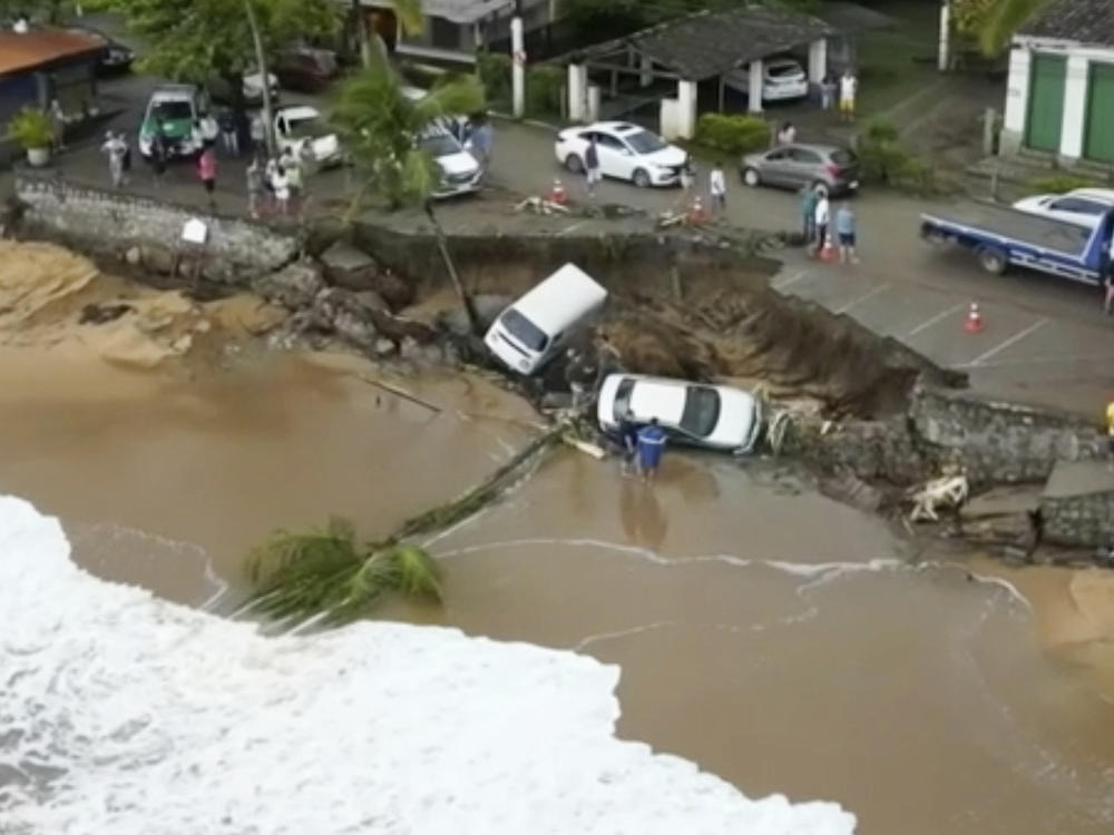 This photo provided by the Sao Paulo Government shows vehicles fallen from an elevated area along the beach in Sao Sebastiao, east of Sao Paulo, Brazil, Sunday, Feb. 19, 2023, after it was damaged by a severe weather system went through the area.