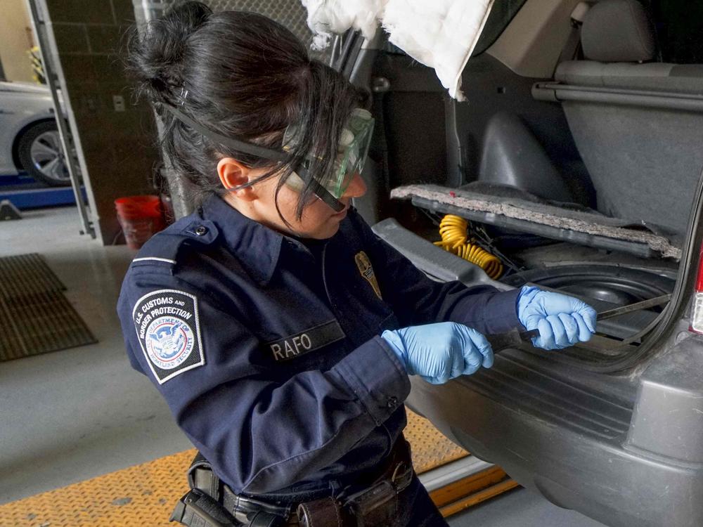 A U.S. Customs and Border Protection agent searches an automobile for contraband in the line to enter the United States at the San Ysidro Port of Entry in October 2019 in San Ysidro, Calif.