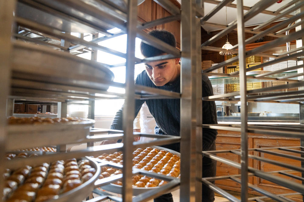 An employee moves fresh baklava onto racks in the front of the restaurant at Imam Cagdas.