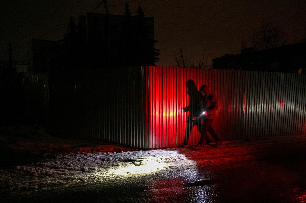 A man uses a flashlight as he walks down a dark street during a blackout in Lviv on Dec. 16, 2022, after Russian strikes targeted the power infrastructure.