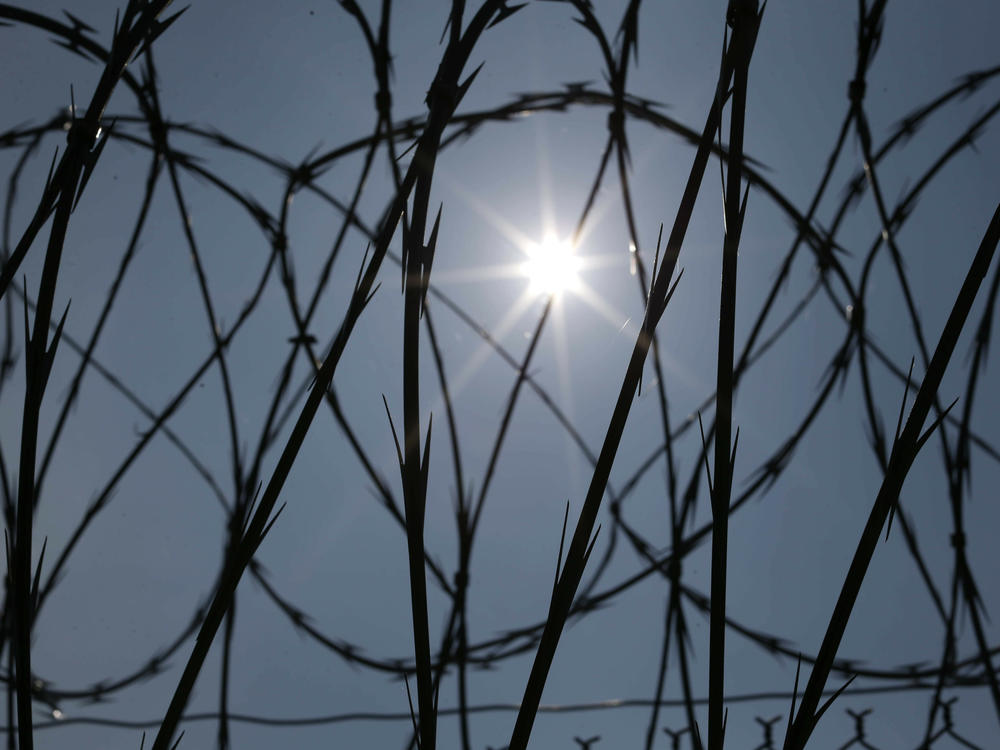 The sun shines through concertina wire on a fence at the Louisiana State Penitentiary in Angola, La., in 2014.