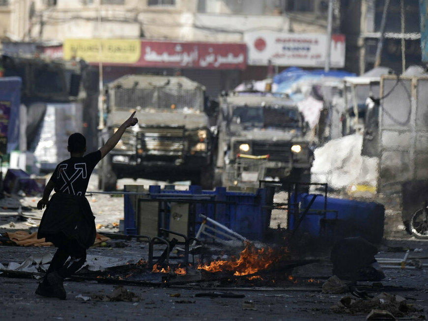 A Palestinian gestures to Israeli military vehicles Wednesday during clashes in the West Bank city of Nablus.