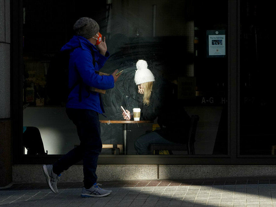 A woman is lit by sunlight Wednesday while sitting inside a coffee shop in San Francisco. A brutal winter storm knocked out power in California, closed interstate highways from Arizona to Wyoming and prompted more than 1,200 flight cancellations Wednesday — and the worst won't be over for several days.