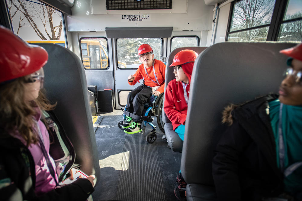 John Buettner (center), talks with classmates on the bus on a field trip to see how playgrounds are designed.