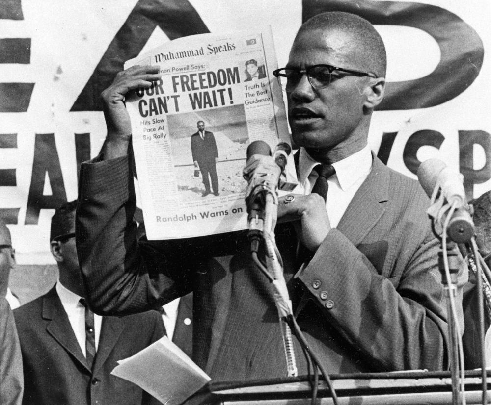 Malcolm X holds up a paper for the crowd to see during a Black Muslim rally in New York City on Aug. 6, 1963.