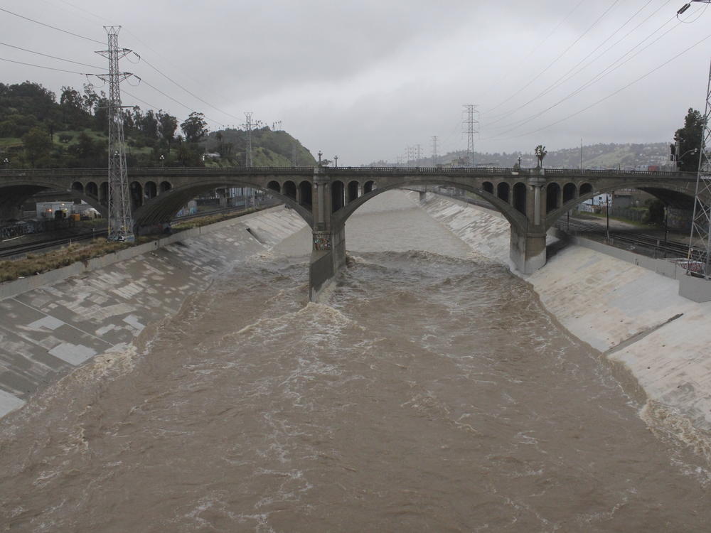 The rain-swollen Los Angeles River flows near downtown Los Angeles on Saturday, as a powerful storm pounds Southern California.