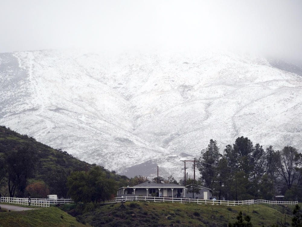 Snow accumulates on a hillside over a property Friday, Feb. 24, 2023, in Agua Dulce, Calif. California and other parts of the West faced heavy snow and rain Friday from the latest winter storm to pound the U.S.
