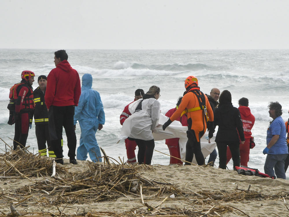 Rescuers recover a body at a beach near Cutro, southern Italy, after a migrant boat broke apart in rough seas, Sunday, Feb. 26, 2023. Rescue officials say dozens of migrants have died after their boat broke apart off southern Italy.