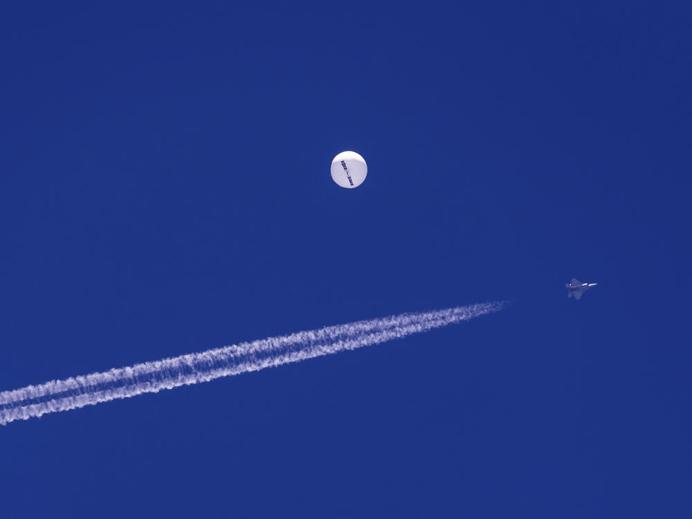 A fighter jet flies near a large balloon drifting above the Atlantic Ocean, just off the coast of South Carolina near Myrtle Beach, Feb. 4. Minutes later, the balloon was struck by a missile from an F-22 fighter jet, ending its weeklong traverse over the United States. China said the balloon was a weather research vessel blown off course, a claim rejected by U.S. officials.