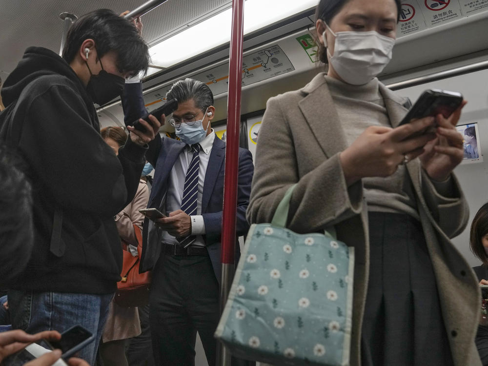 Commuters wearing face masks browse their smartphones as they ride on a subway train in Hong Kong on Feb. 7, 2023. Hong Kong will lift its mask mandate Wednesday, March 1, 2023, ending the city's last major restriction imposed during the COVID-19 pandemic.